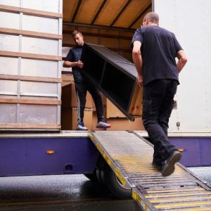 removal people are carrying a piece of furniture out of a truck. A divorce or separation can involve moving house which can impact your age pension
