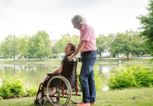 A couple talking through retirement plans. One is sitting in a wheelchair looking at the other person.